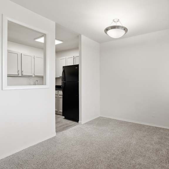 a room with a carpeted floor and a black refrigerator.