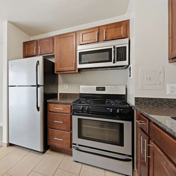 a kitchen with a white fridge, stainless steel oven, and microwave.