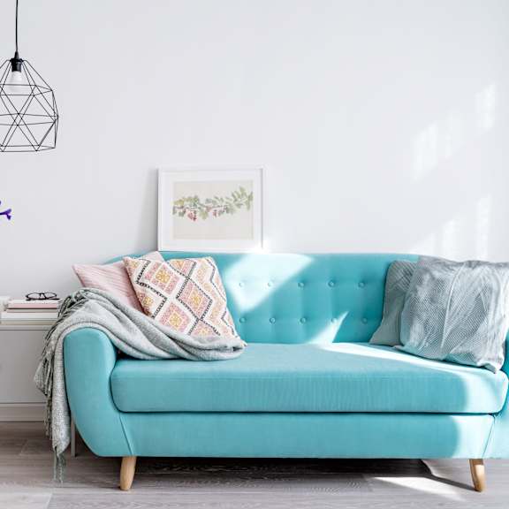 a blue couch with a pillow and a blanket on it.