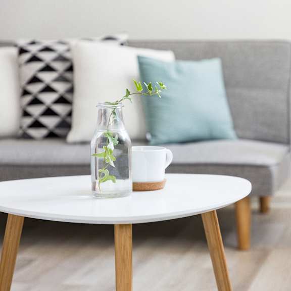 a living room with a grey couch, a white coffee table, and a wicker chair.