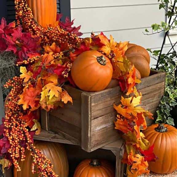 a wooden crate filled with pumpkins and leaves.