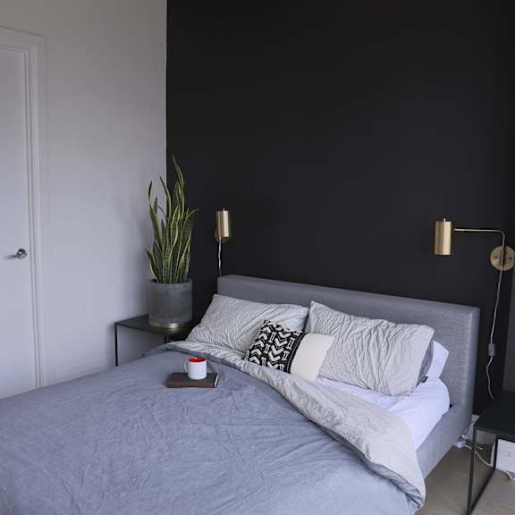 a bedroom with a bed and a black wall