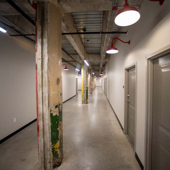 a view down a long corridor with white walls and grey doors at conwood flats, memphis, tn, 38107
