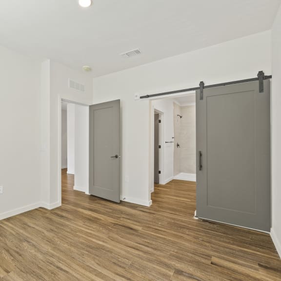 Thumbnail 5 of 14 Bedroom with wood floors and barn door feature at Azalea, Luxury Tampa Apartments