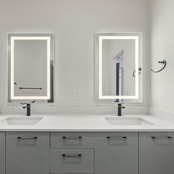 Thumbnail 14 of 14 Luxury bathroom with double sinks and two ring light mirrors at Azalea Luxury Tampa Apartments