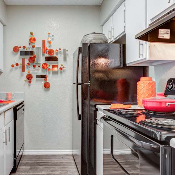 kitchen with white cabinets and black appliances at the enclave at woodbridge apartments in sugar land