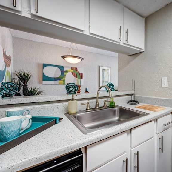 a kitchen with white cabinets and a stainless steel sink at sundance apartments, college station, texas
