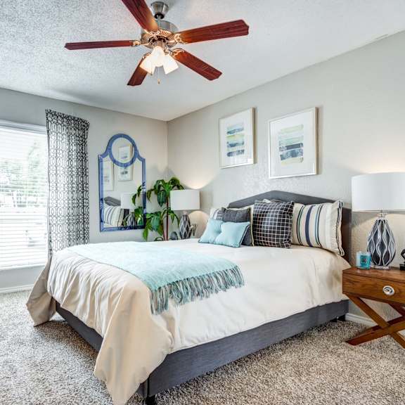 a bedroom with a large bed and a ceiling fan at sundance apartments, college station, tx, 77840