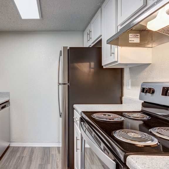 a kitchen with white cabinets and stainless steel appliances at sundance apartments, texas