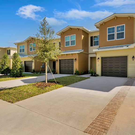 a house with two garages and a tree in the middle of a driveway
