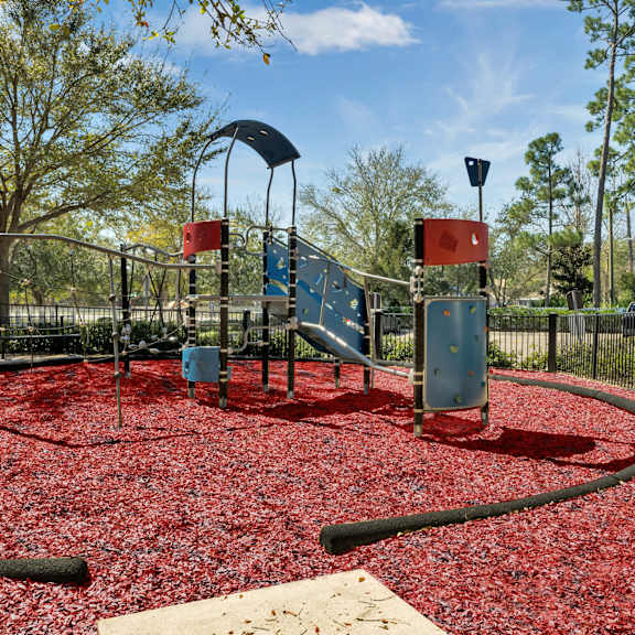 a playground with a slide and red mulch