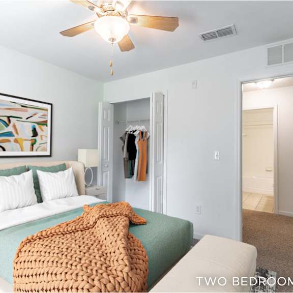 a bedroom with a bed, a ceiling fan, and a painting on the wall.