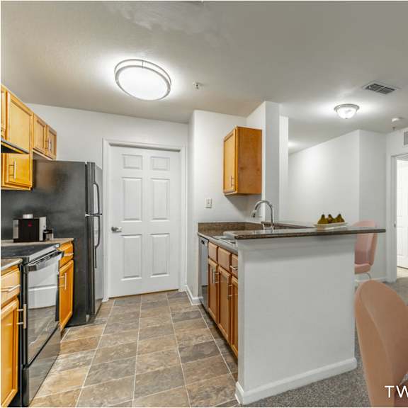 a kitchen with a black refrigerator and wooden cabinets.