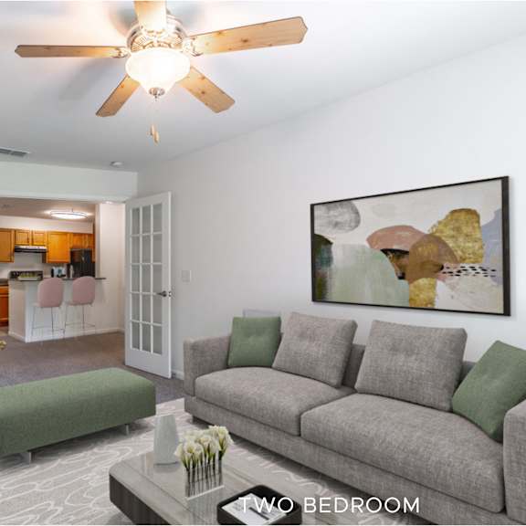 a living room with a grey couch and a ceiling fan.