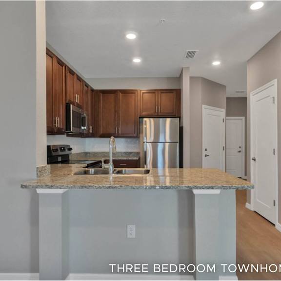 a kitchen with granite countertops and wooden cabinets.