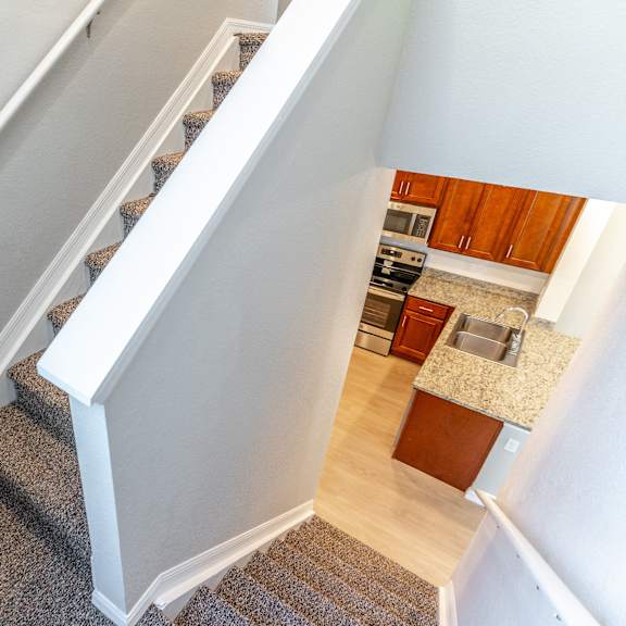 a view from the top of the stairs looking down into the kitchen and living room