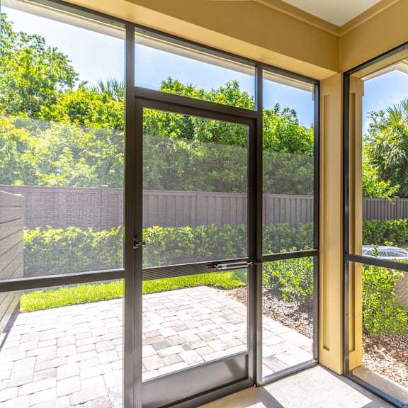 a large sliding glass door opens to a patio with a brick walkway