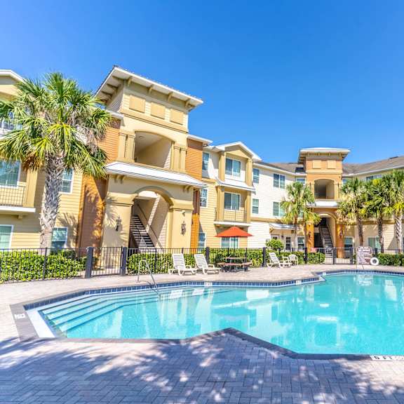 a swimming pool with palm trees in front of a building