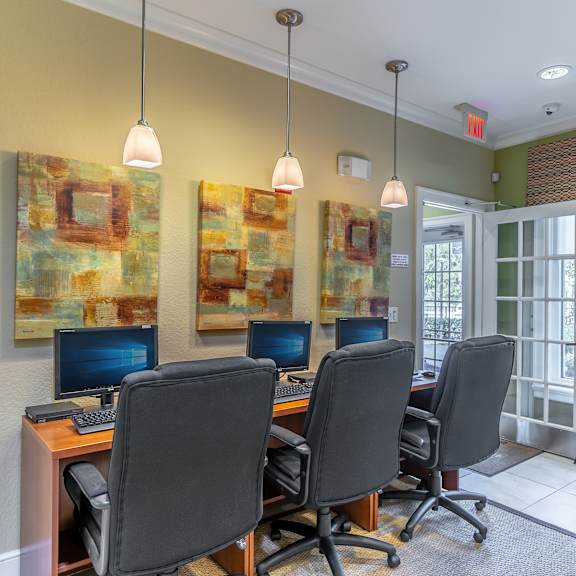 a desk with four computers in a room with green walls and a glass door