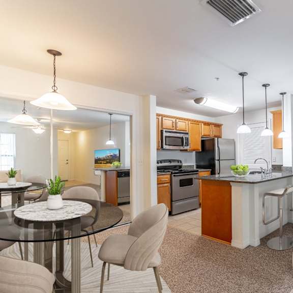 a living room with a table and chairs and a kitchen in the background