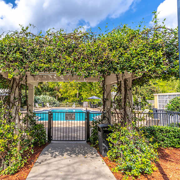 a pergola with a walkway leading to a pool