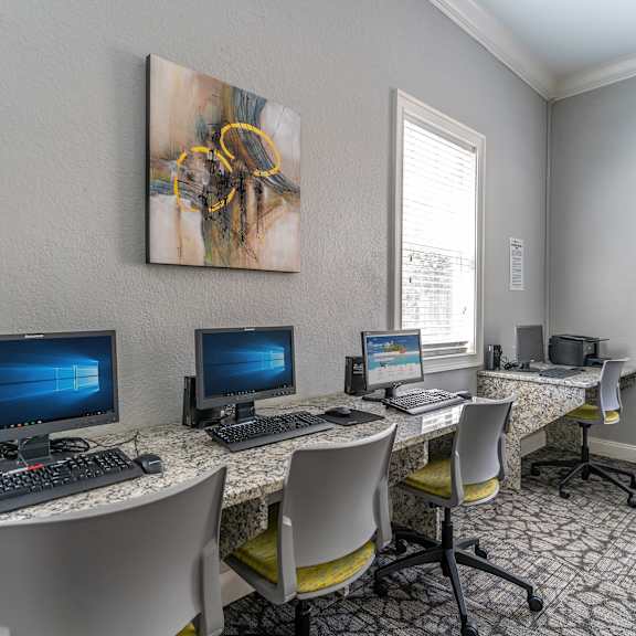 a computer room with three computers and chairs