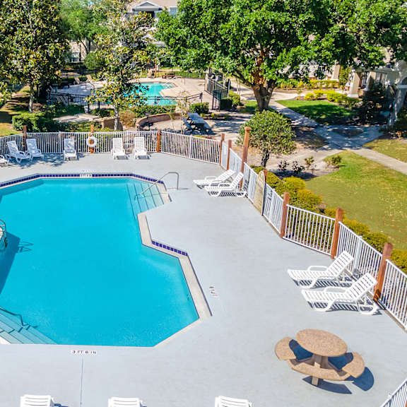 an aerial view of the resort style pool with chaise lounge chairs and trees in the background