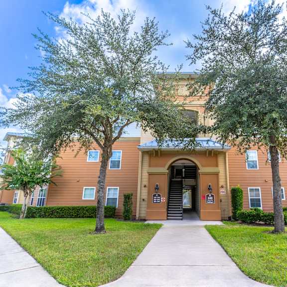 a building with a sidewalk and trees in front of it