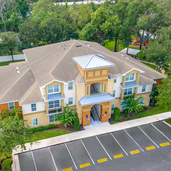 an aerial view of a large yellow house with a parking lot and trees