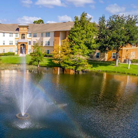 a fountain sits in the middle of a pond in front of a building