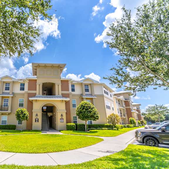 a large, beige apartment building with a green lawn in front.