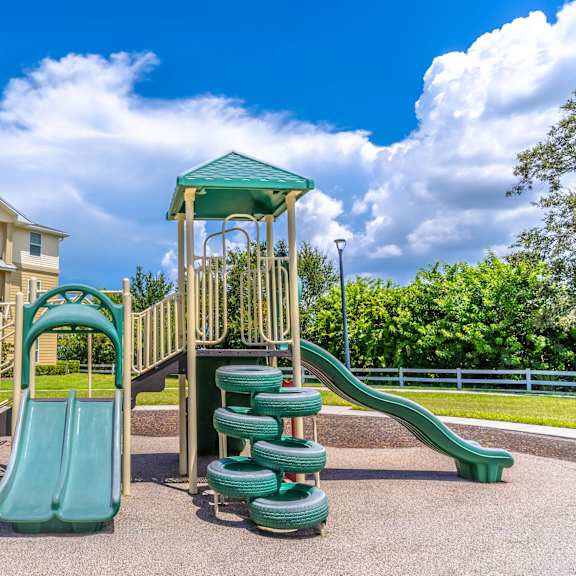 a playground with a green slide and a wooden structure.