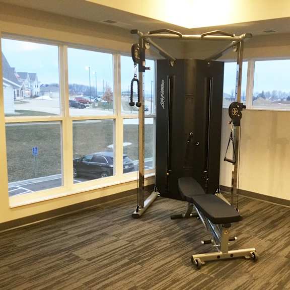 a gym with a weight bench in a room with windows