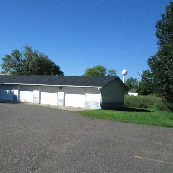 a large white building with a grey roof is surrounded by a paved area.