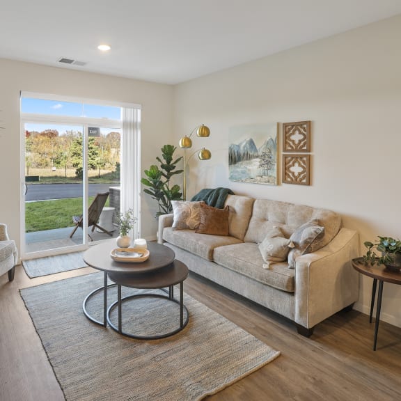 a living room with a couch and two chairs, a tv and large sliding glass doors leading outside
