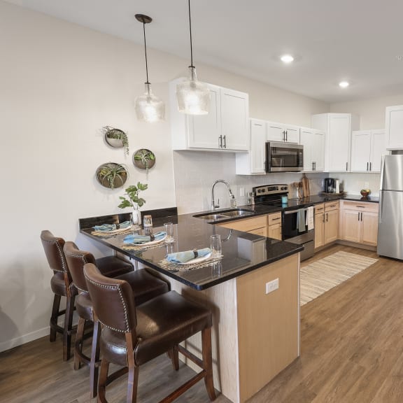 a kitchen with stainless steel appliances and a island with chairs