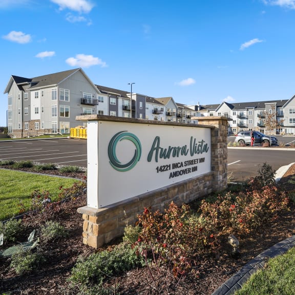 an apartment building with a sign in front of a parking lot