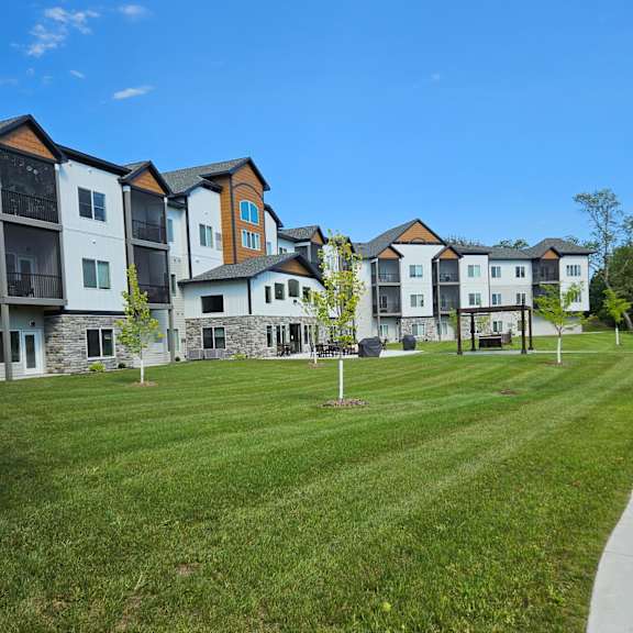 a row of multi-story apartment buildings with a grassy lawn in front.