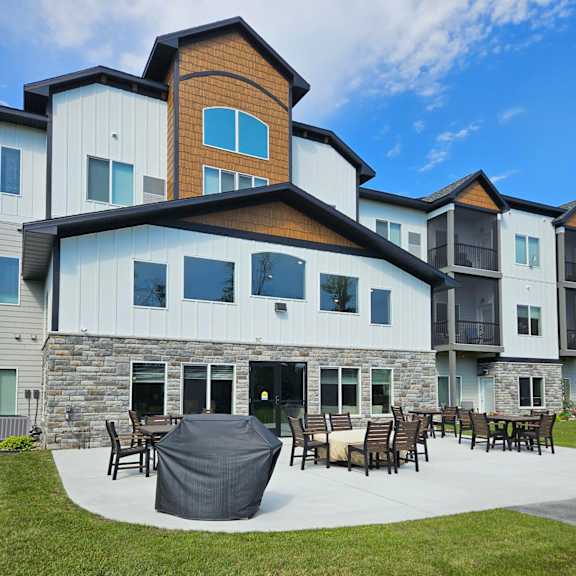 a modern house with a stone and wood exterior and a patio with furniture.