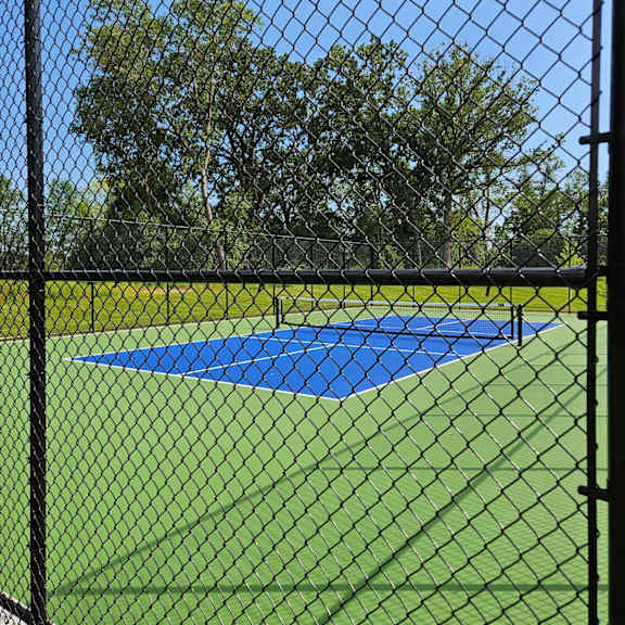 a tennis court is enclosed by a black fence.