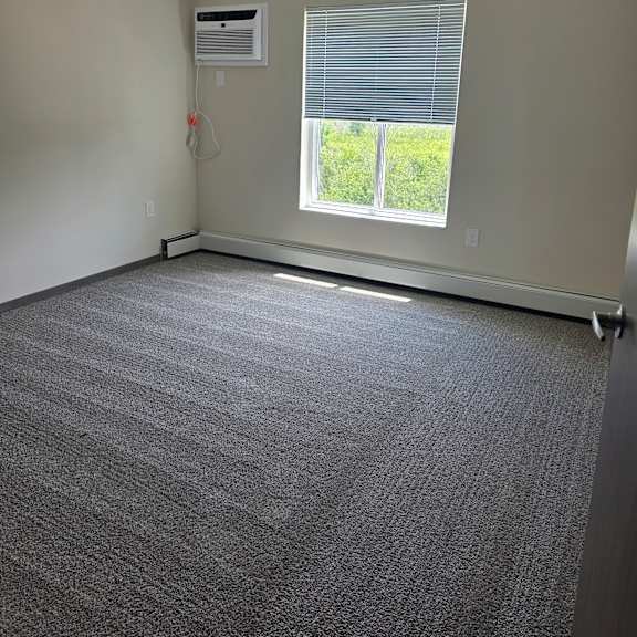 a bedroom with a window and a wall-mounted air conditioner unit.