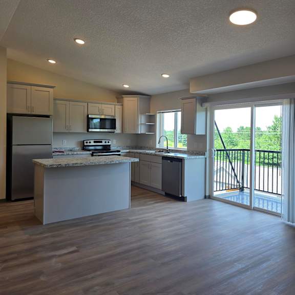 a modern kitchen with wooden floors and white walls.