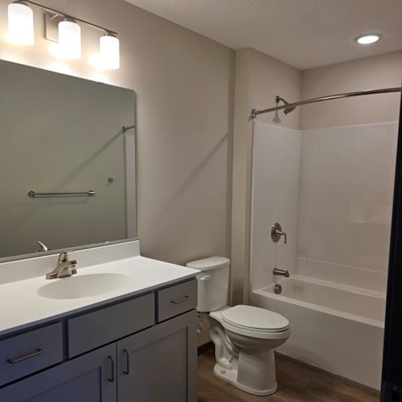 a bathroom with a toilet, sink, and mirror.