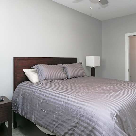 a bedroom with a bed, nightstand, and lamp.