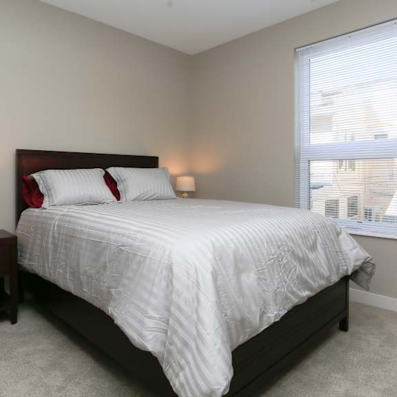 a bedroom with a bed, nightstand, and window.