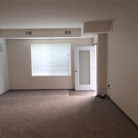 an empty living room with a door and a window