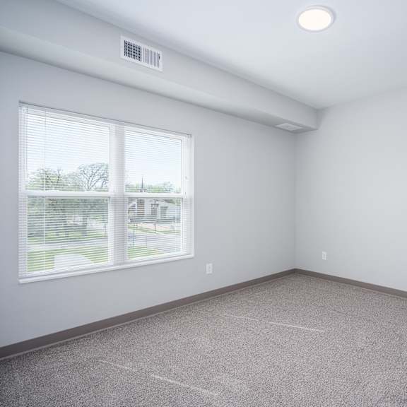 an empty room with a large window and carpet