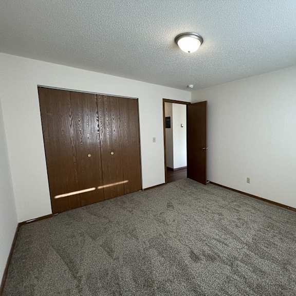 a room with a carpeted floor and two wooden doors.