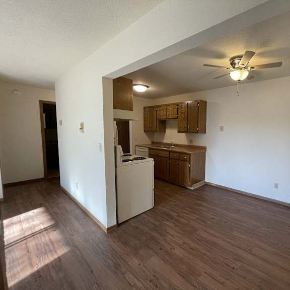 a kitchen area with a refrigerator, cabinets, and a ceiling fan.