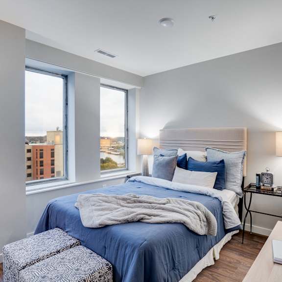 a bedroom with a large bed and a window overlooking a cityscape.